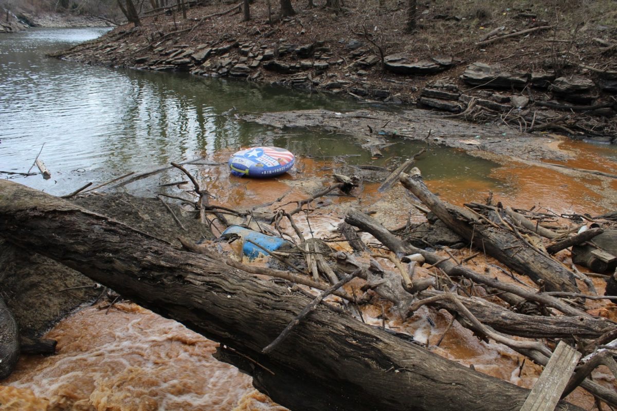 rust-colored water flowing into a stream, litter