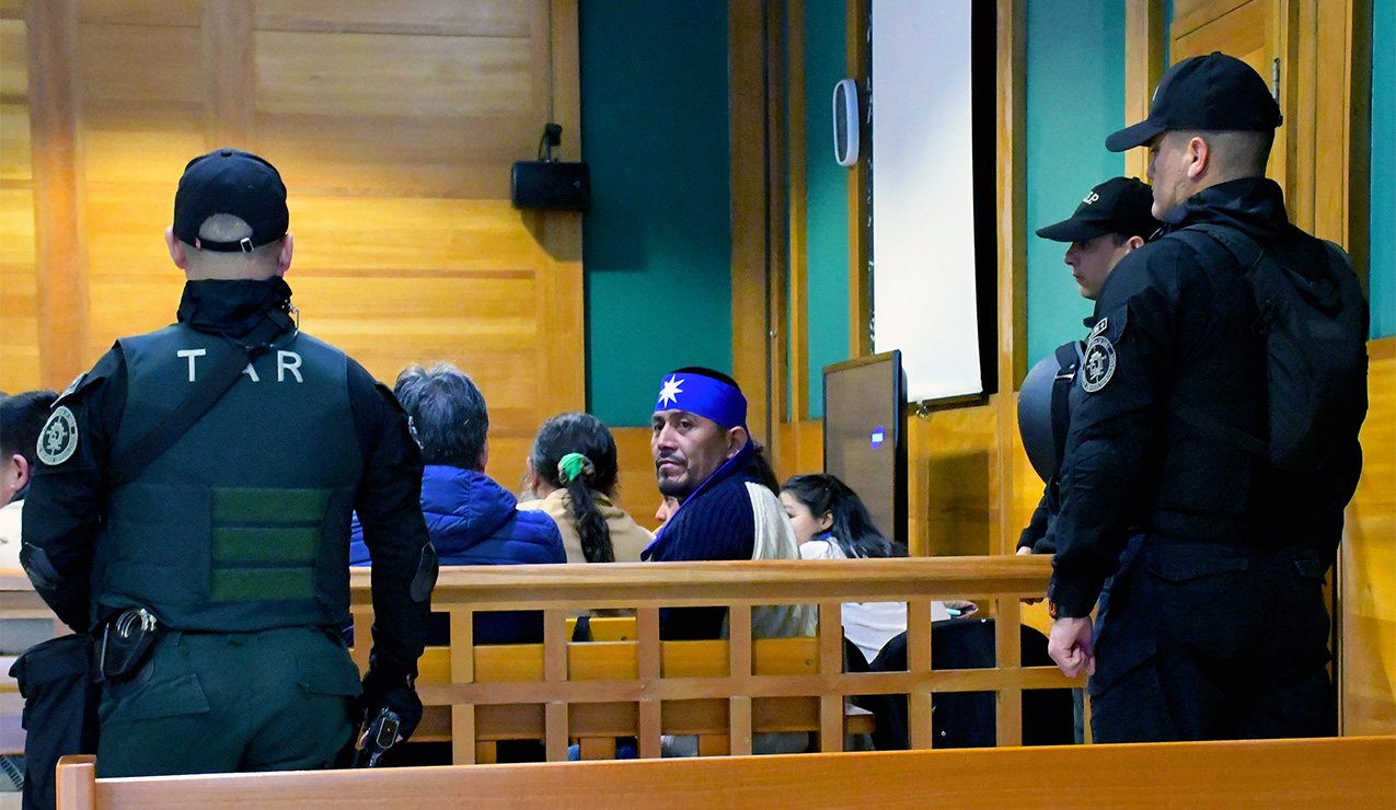 Alberto Curamil in a courtroom surrounded by armed guards