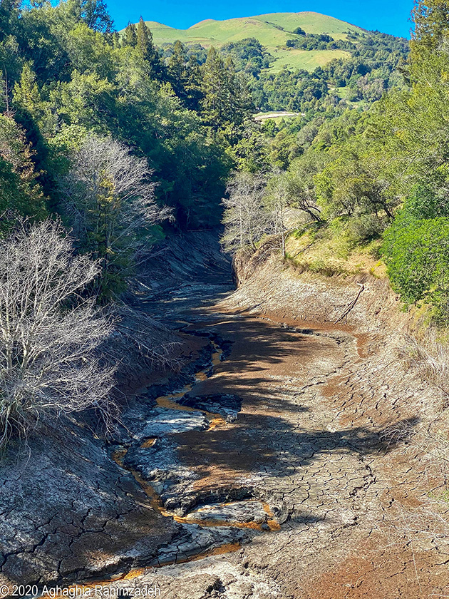 A dry lake bed, site of a former reservoir that has had its water pumped out