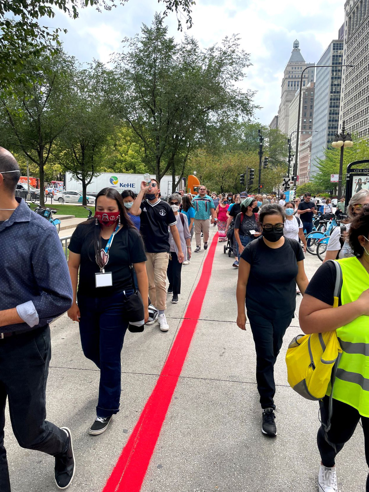 Participants of the public art performance “Whose Lakefront” walk along a line of red sand that was poured in downtown Chicago to bring attention to the land taken from the Pokagon Band of Potawatomi Indians