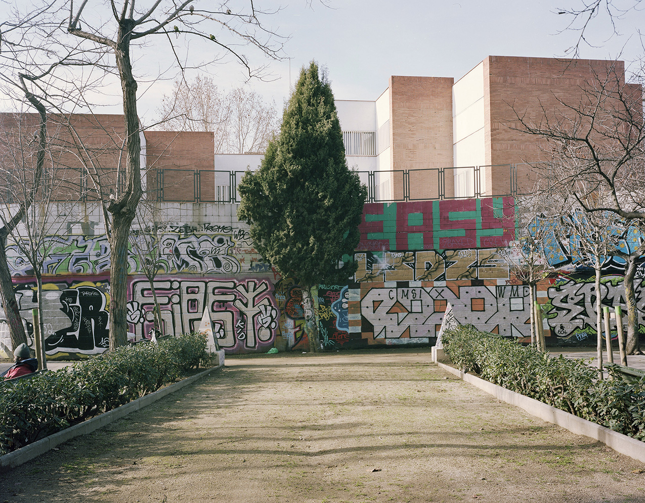 symmetrical walkway leading to a wall covered with graffiti, the most prominent word is "EASY"
