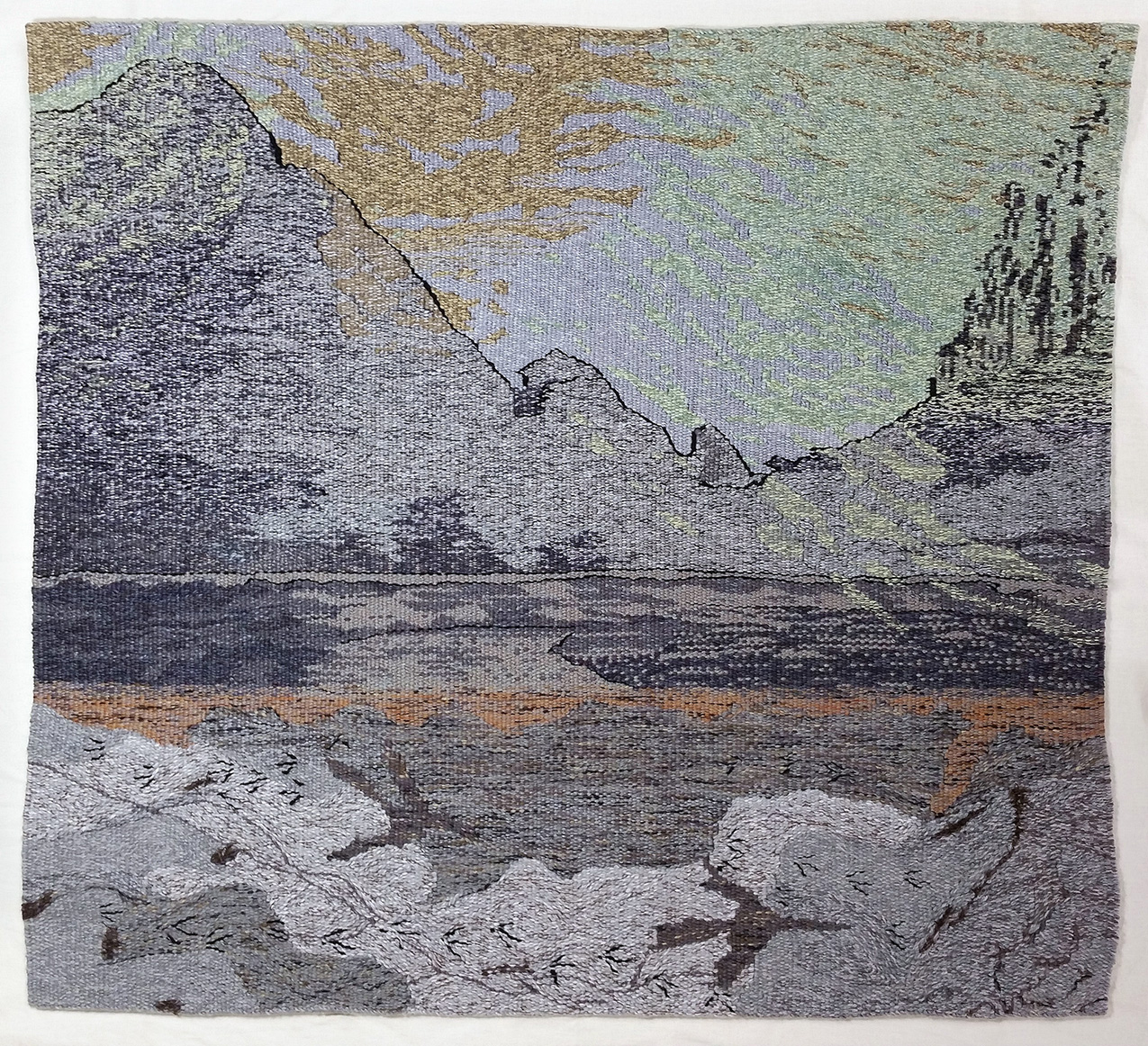 handwoven tapestry depicting a canyon’s cliffs superimposed over a view looking straight down onto the river and its bank marked with tracks of turkeys, smaller birds, and insects. colors are mostly gray with muted shades of rush, gold, light green, and deep blue-purple.