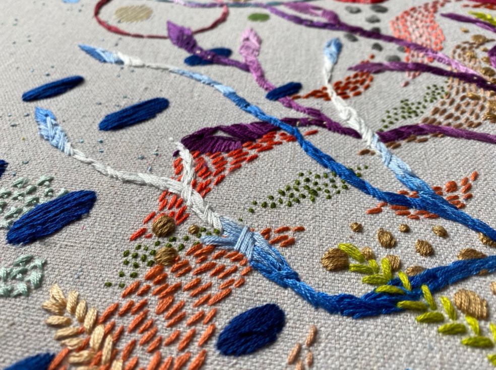 closeup of underwater seascape embroidery featuring crisscrossing lines and textures in many bright colors