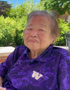 photo of the author's Popo (Grandma), an elderly Chinese woman wearing a purple shirt with a W embroidered