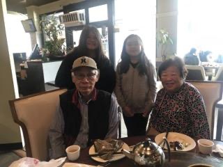 a family (child, teen, and two adults) poses for a photo at a restaurant