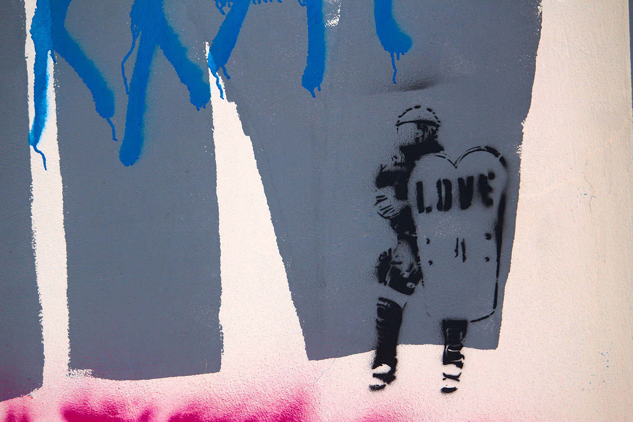 graffiti featuring a person in riot gear with LOVE stenciled on their riot shield