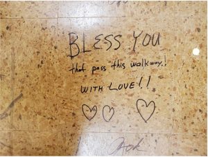 handwritten message on a floor tile reads "BLESS YOU that pass this walkway, with LOVE!!"