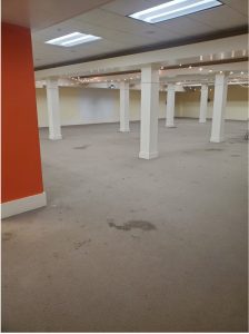 Large empty room with stained carpet
