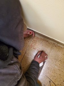 looking over the shoulder of a person in a hoodie writing on a psalm on a floor tile with red sharpie