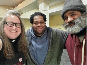 a female pastor and two adult men in hoodies take a selfie
