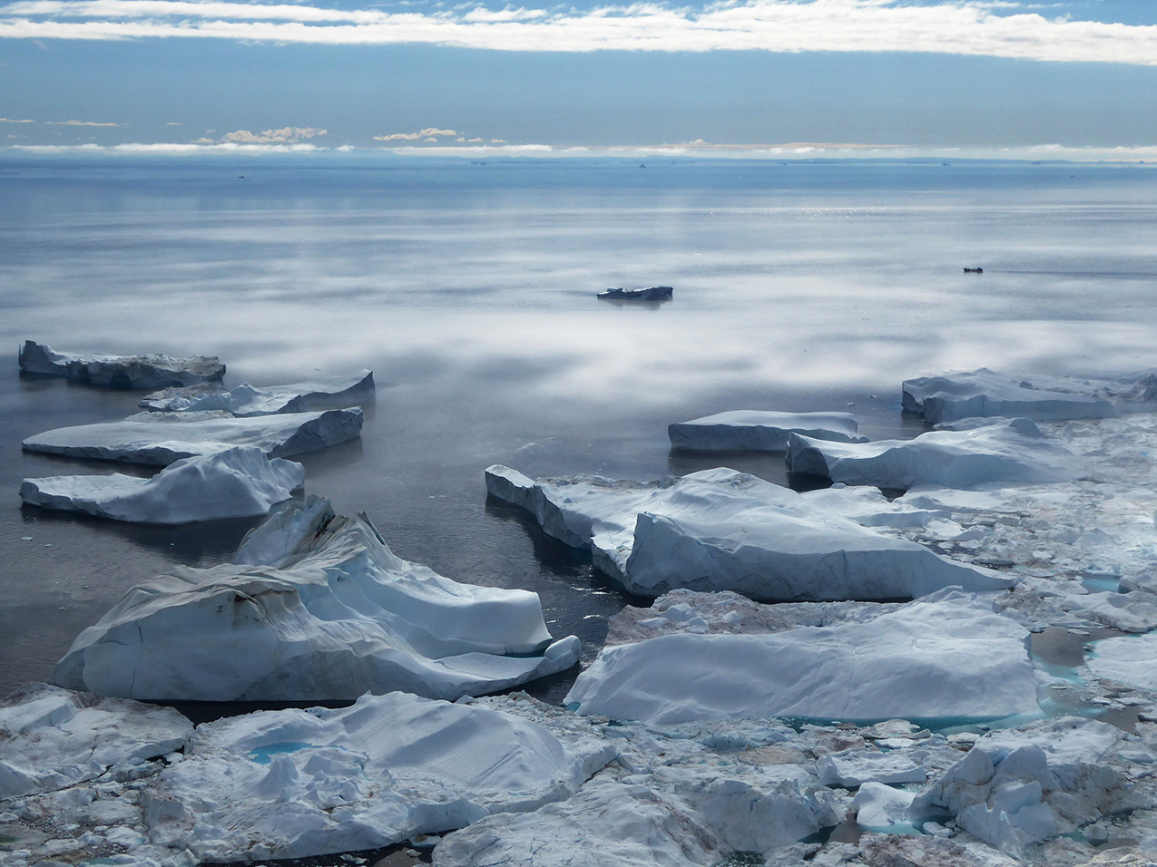 huge iceberg-like chunks in the foreground meet a misty body of water that stretches to the horizon.